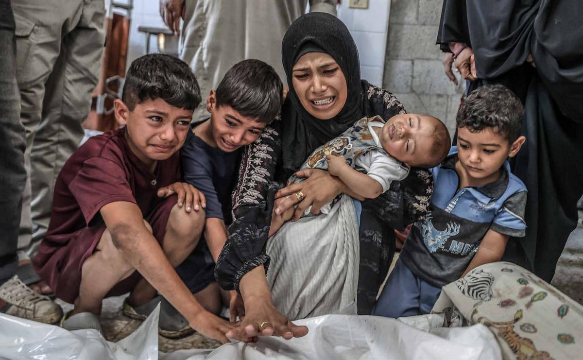 The bodies of Palestinians killed in an Israeli military attack have been brought to Al-Aqsa Martyrs Hospital in Deir al-Balah for burial. Relatives of the deceased mourn beside the coffins.