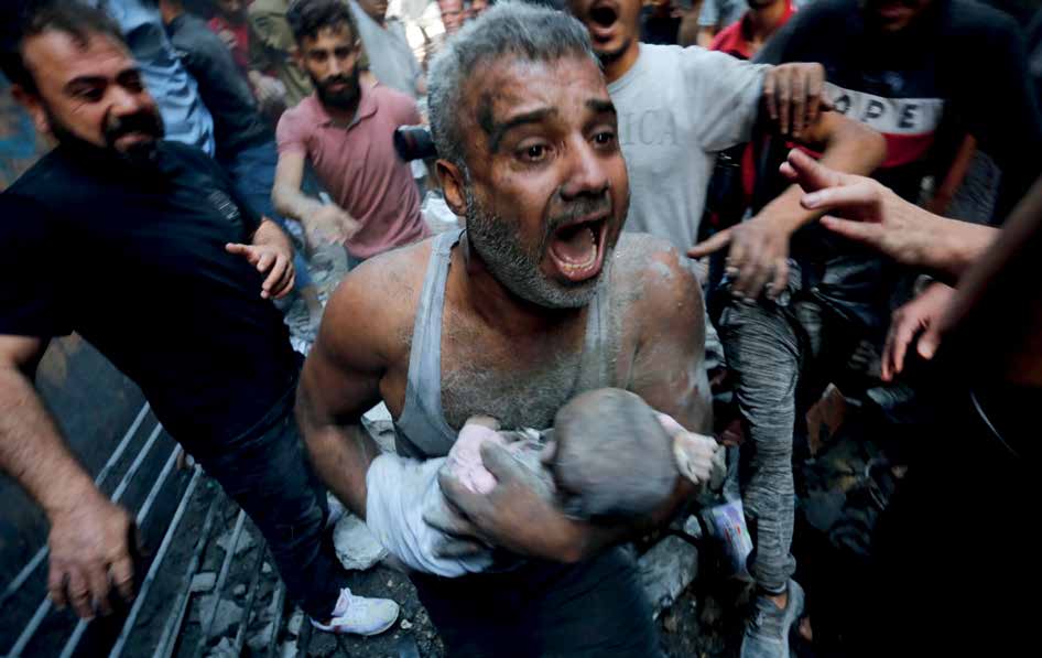 A Palestinian man carrying the body of a baby killed in the Israeli attack on the Al-Shati Refugee Camp.