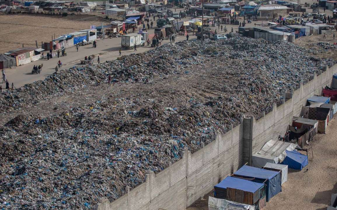 As the hunger and fuel crises deepen in the southern Gaza Strip city of Khan Yunis, pollution from surrounding trash and various types of waste is also increasing. Palestinians are sifting through piles of garbage to collect wood, paper, and cardboard for use as fuel.