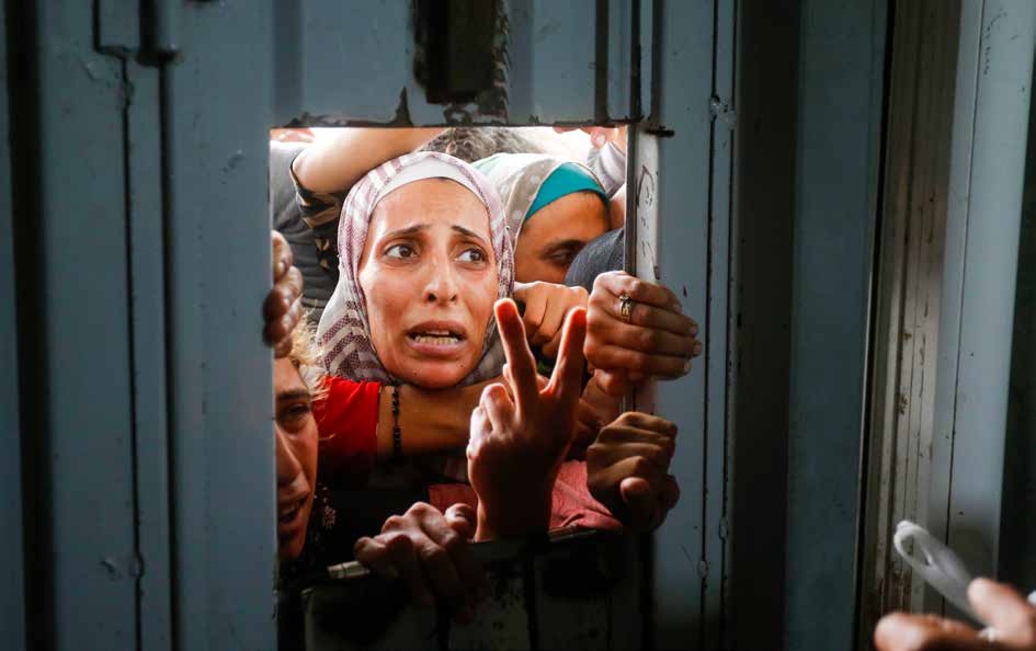 Hundreds of Palestinians wait in harsh conditions outside a bakery in Deir al-Balah, Gaza, hoping for their turn to buy bread. Over a year of Israeli attacks, the closure of border crossings, and restricted access to aid have left Palestinians struggling with hunger.