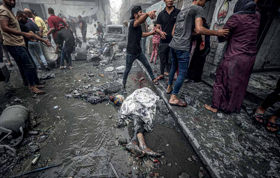 A Palestinian youth, killed in the Israeli army’s air strikes on the Ridwan neighborhood of Gaza, lies on the ground, covered by the survivors.