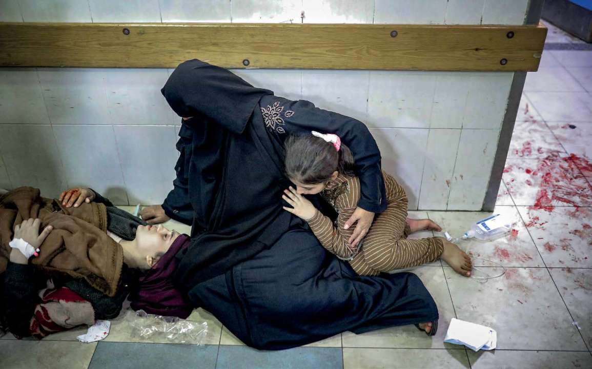 At the Nasser Hospital, a Palestinian mother waits by her older daughter, who sustained injuries during an Israeli army attack, accompanied by her younger daughter.